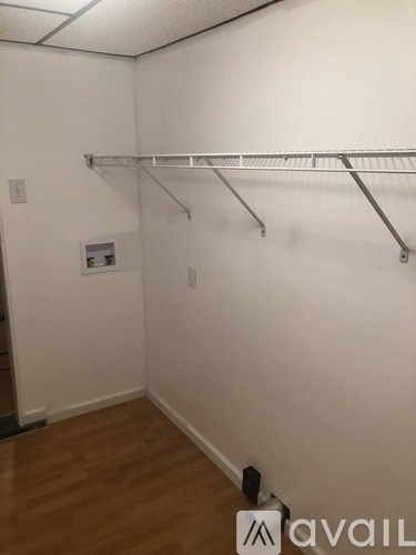 A white wall with a shelf and a black speaker on the floor.