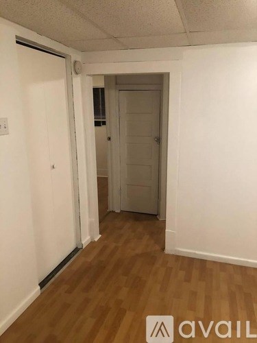 A hallway with a door on the right and a light switch on the wall.
