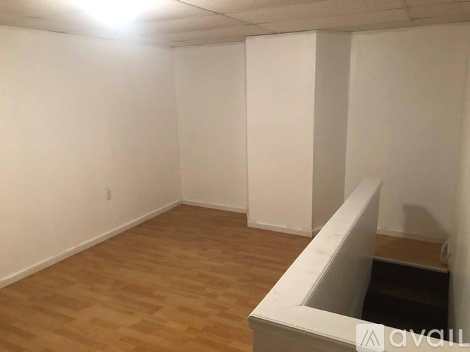 A room with wooden flooring and white walls, with a light source coming from the ceiling.