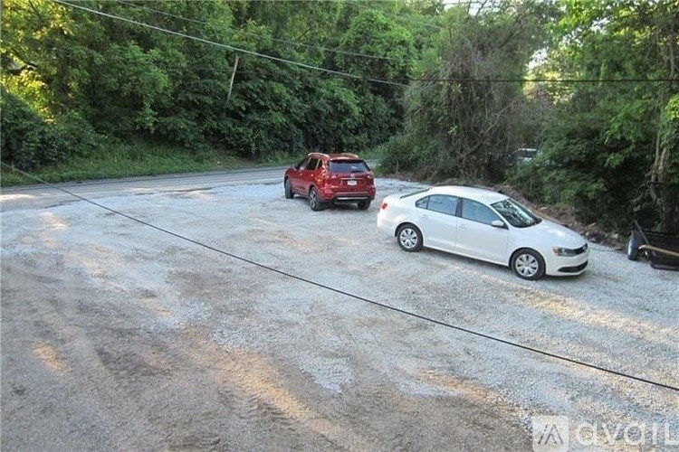 Two cars are parked on a dirt road.