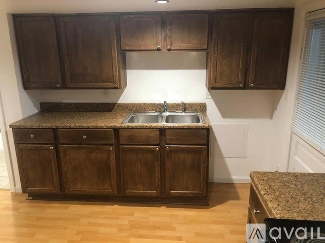 A kitchen with brown cabinets and a granite countertop.