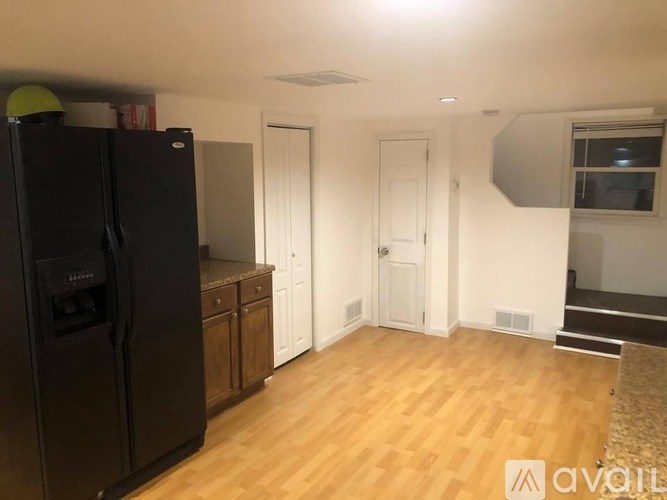 A kitchen with a black fridge and wooden floors.