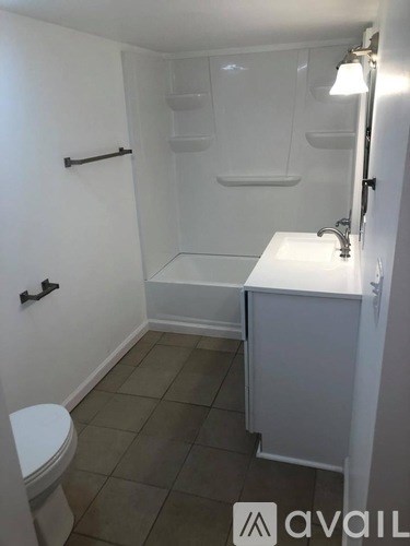 A small white bathroom with a toilet, sink and shower.
