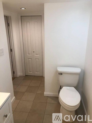 A white toilet in a small bathroom with a white door in the background.