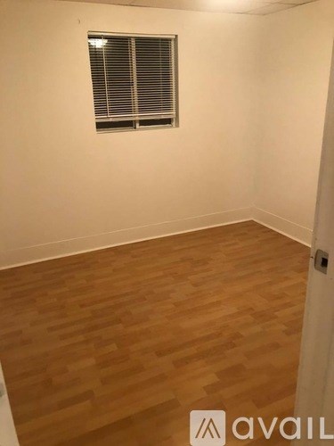 A room with wooden flooring and a window with blinds.