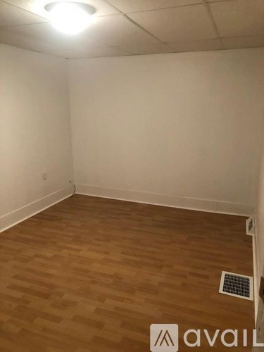 A room with wooden flooring and a white wall.