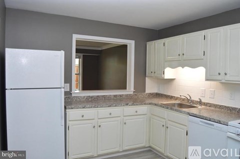 A kitchen with white cabinets and a white refrigerator.