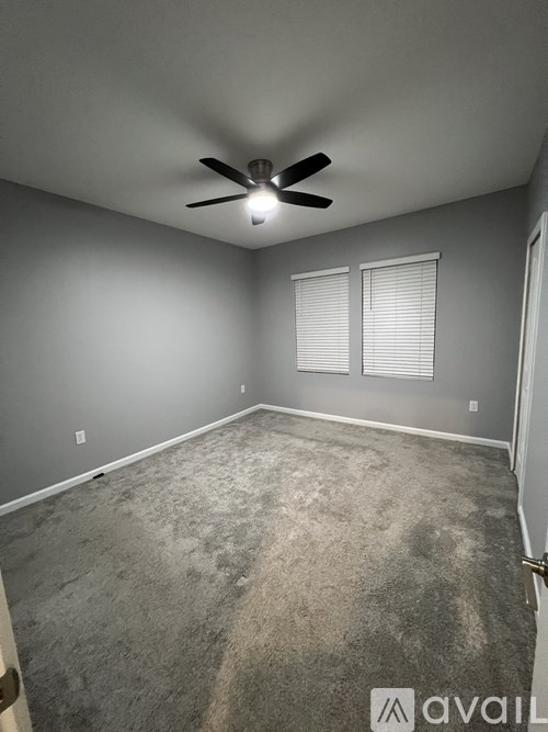A room with a ceiling fan and carpeted floor.