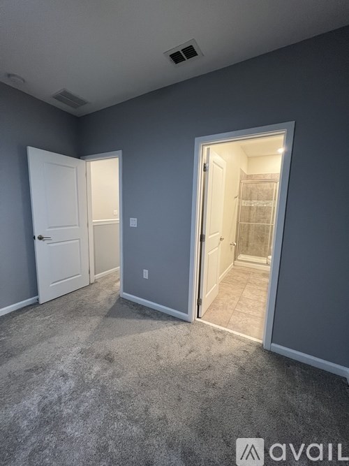 A room with a carpeted floor and two doors, one of which is open.