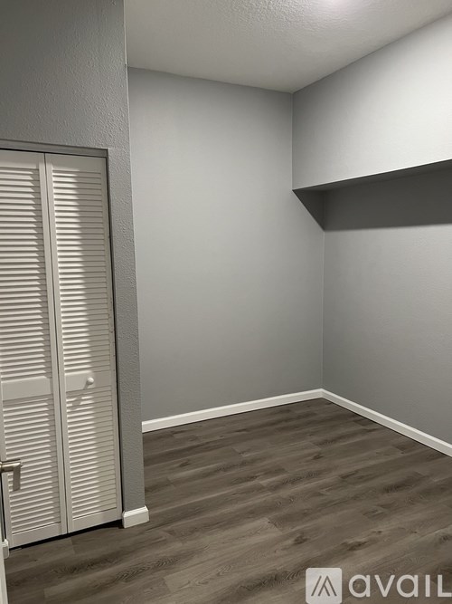 A room with a white door and wooden floor.