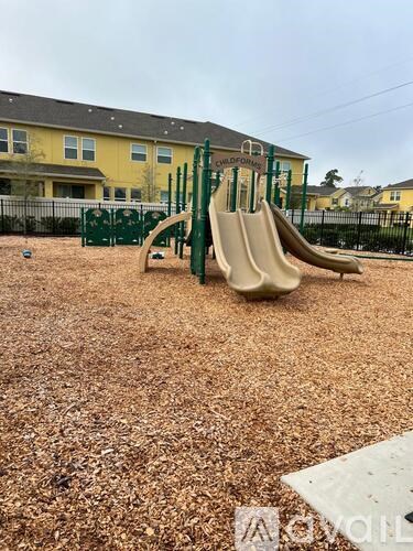 A playground with a slide and a green fence.