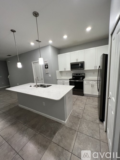 A kitchen with a white island and black appliances.