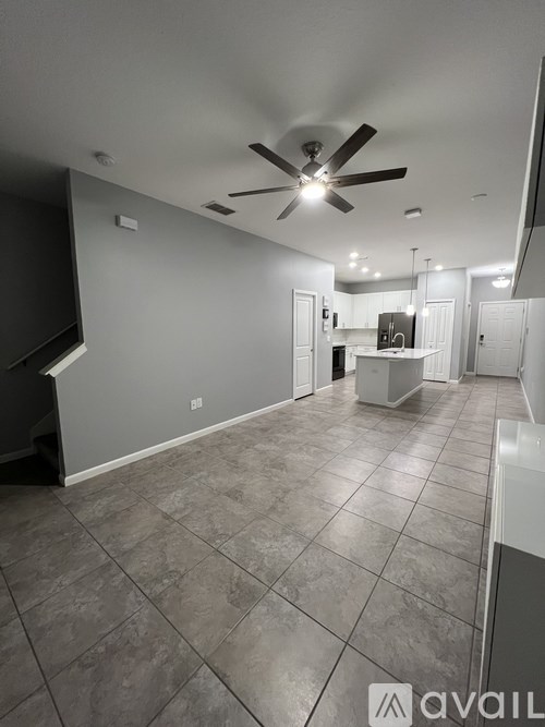 A spacious room with a ceiling fan and tiled flooring.
