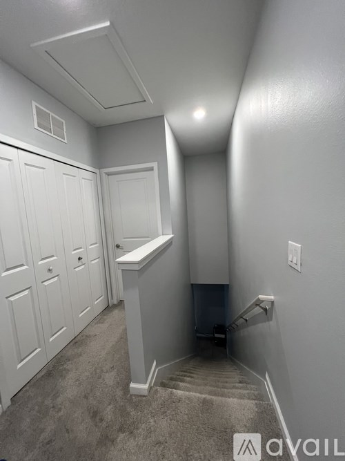 A hallway with a staircase leading to a door at the end.