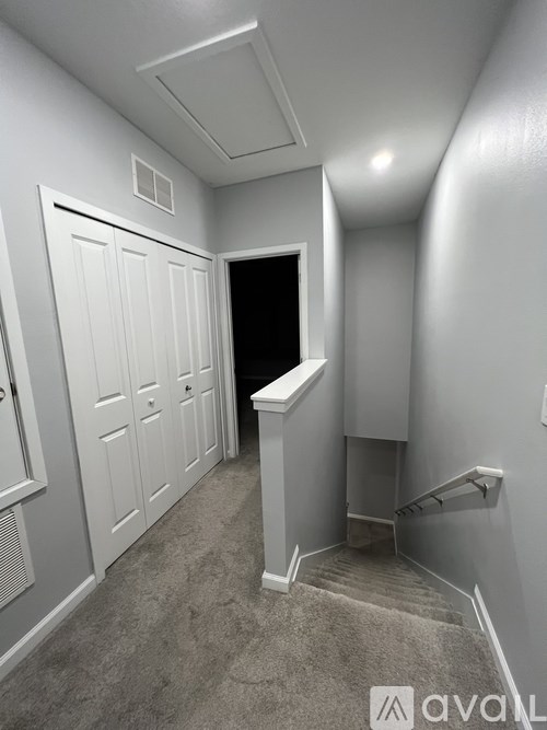 A hallway with a carpeted floor and a staircase leading to the second floor.