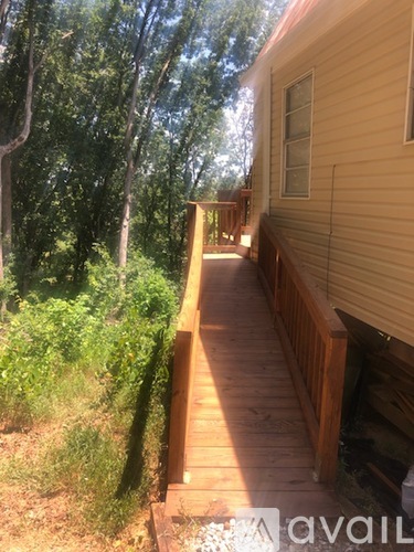 A wooden deck leads to a house in a wooded area.