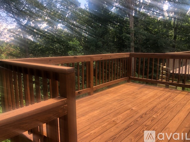 A wooden deck with railings and a view of trees.