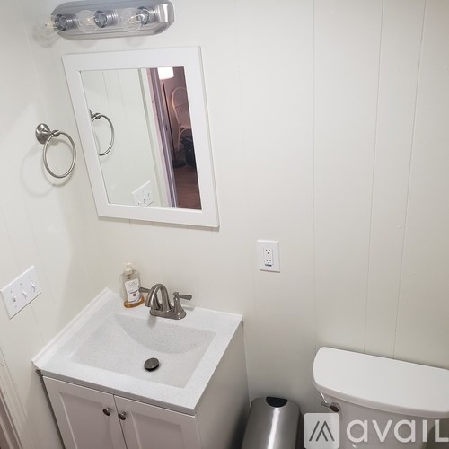 A bathroom with a sink, mirror, and toilet paper holder.
