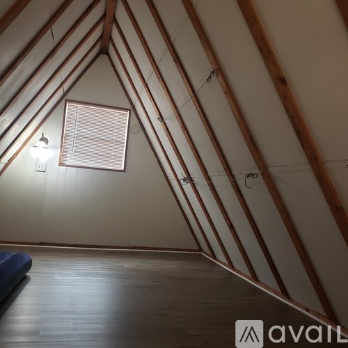 A room with wooden beams on the ceiling and a window with blinds.