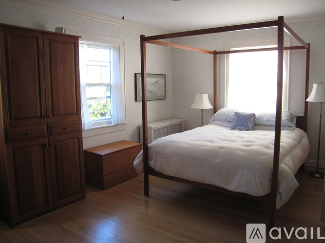 A bedroom with a four poster bed and a wooden cabinet.