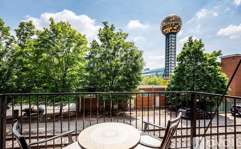 A view of a cityscape with a tall tower and a table and chairs in the foreground.