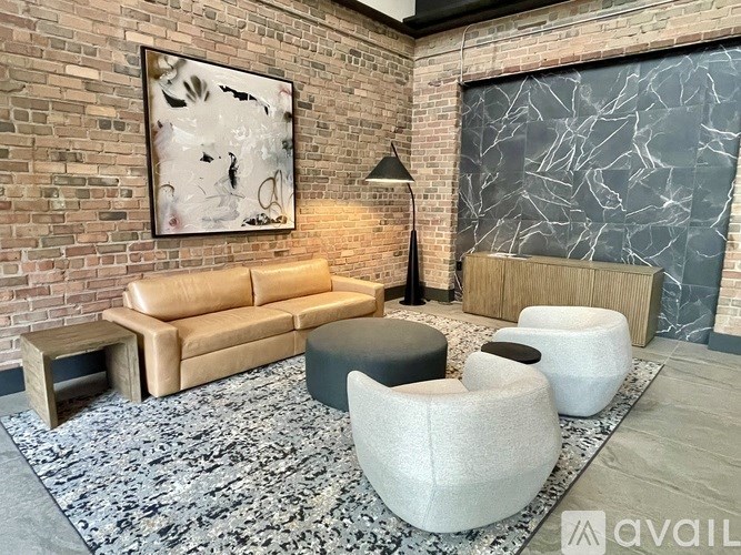 A living room with a leather couch, a coffee table, and a large abstract painting on the wall.
