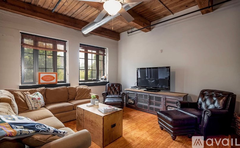 A living room with a brown couch, a brown leather chair, a wooden cabinet, and a television.