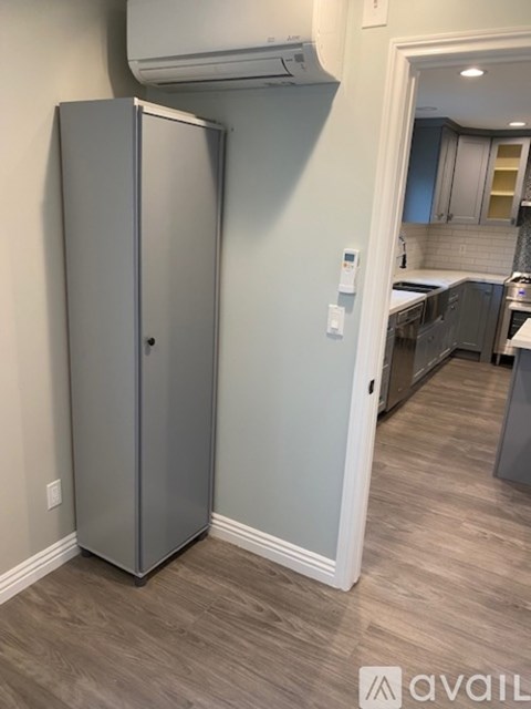 A tall, grey, metal cabinet stands in a kitchen.