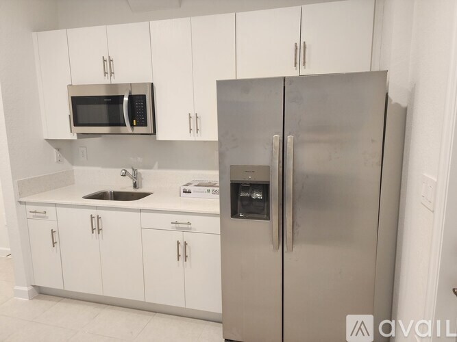 A kitchen with white cabinets and a stainless steel refrigerator.