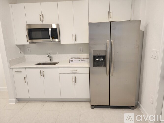A kitchen with white cabinets and a stainless steel refrigerator.
