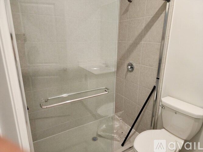 A bathroom with a toilet, glass shower door, and a glass door.
