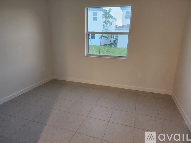 A room with a window showing a view of a house and a lawn.