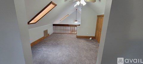 A spacious room with a carpeted floor and a ceiling fan.