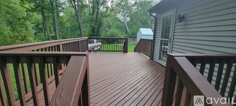 A wooden deck with a railing and a small shed in the background.