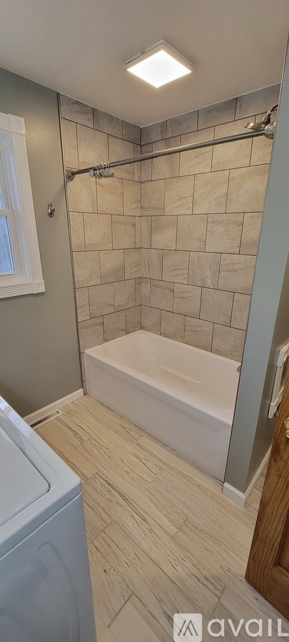 A bathroom with a tiled shower and a white bathtub.