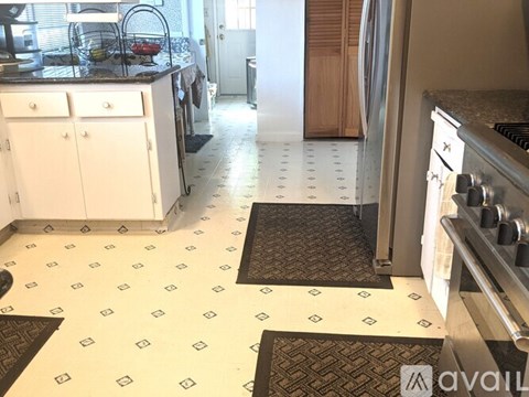 A kitchen with white cabinets and a black and white floor.
