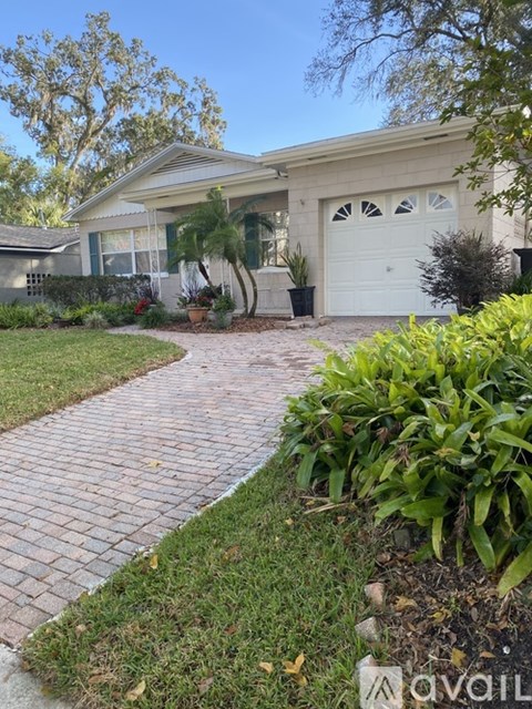 A house with a white garage door and a brick pathway leading to it.
