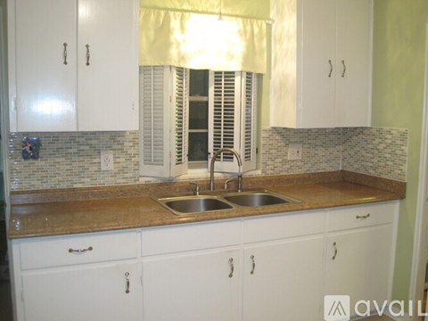 A kitchen with white cabinets and a brown countertop.