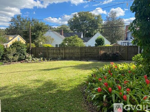 A backyard with a wooden fence and a flower bed in the foreground.
