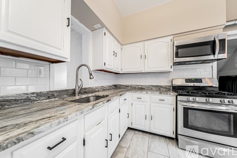 A kitchen with white cabinets and a granite countertop.