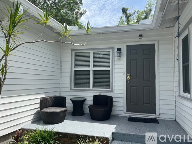 A white house with a black door and a small patio area.