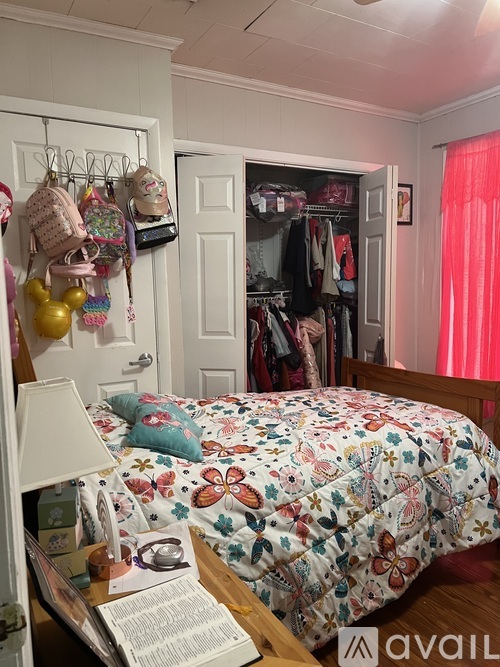 A bedroom with a floral bedspread and a closet full of clothes.