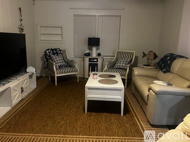 A living room with a white sofa, two striped chairs, and a white coffee table.