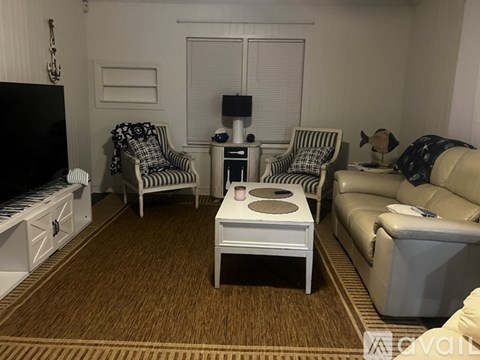 A living room with a white sofa, two striped chairs, and a white coffee table.