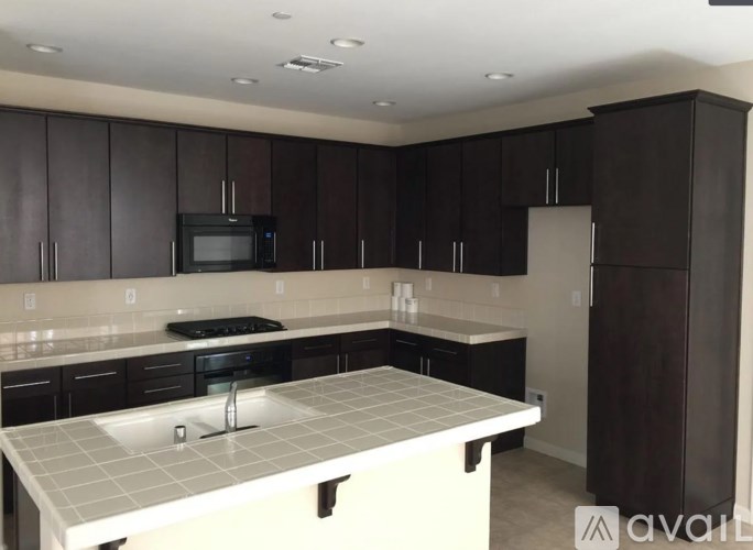 A kitchen with black cabinets and a white countertop.