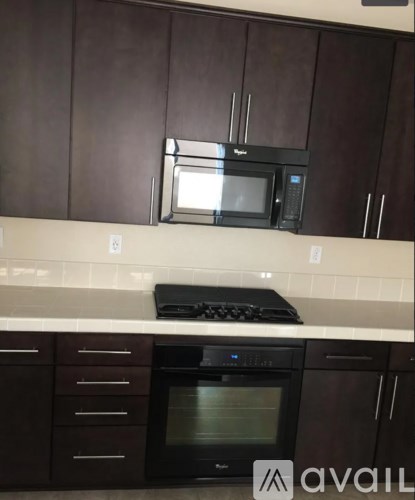 A kitchen with brown cabinets and a black stove top oven.