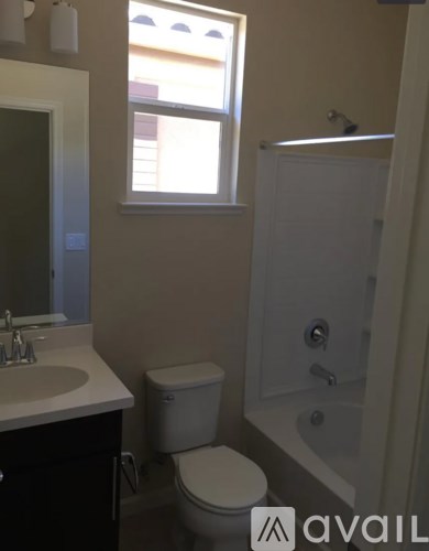 A bathroom with a toilet, sink, and window.