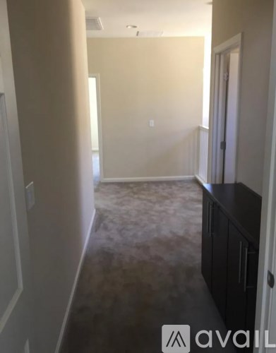 A hallway with a carpeted floor and white walls.