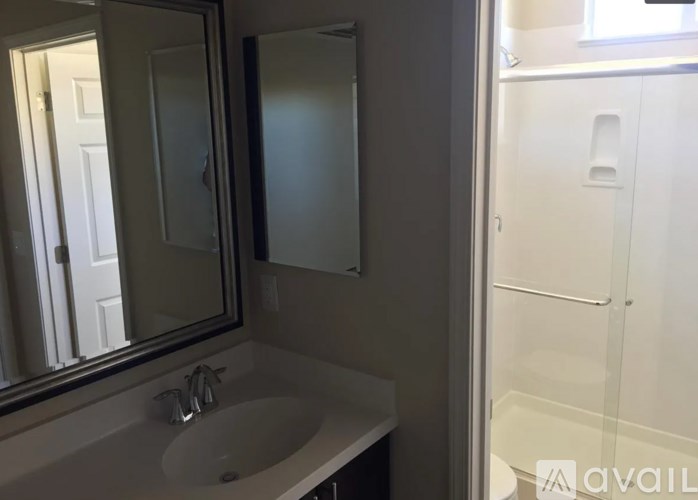 A bathroom with a sink, mirror, and shower.