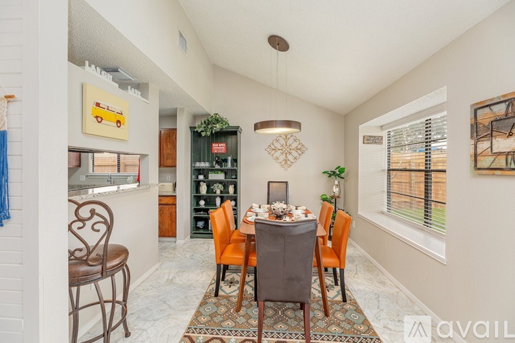 A dining room with a table set for four and a chandelier hanging from the ceiling.